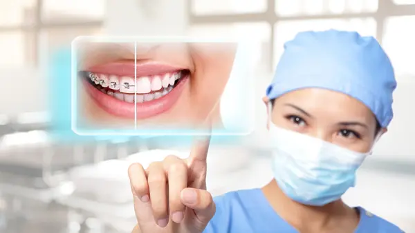 Orthodontist pointing to image of smile wearing braces